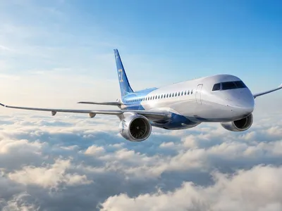 Jato comercial Embraer E2 em voo acima das nuvens, visto de frente e em destaque.